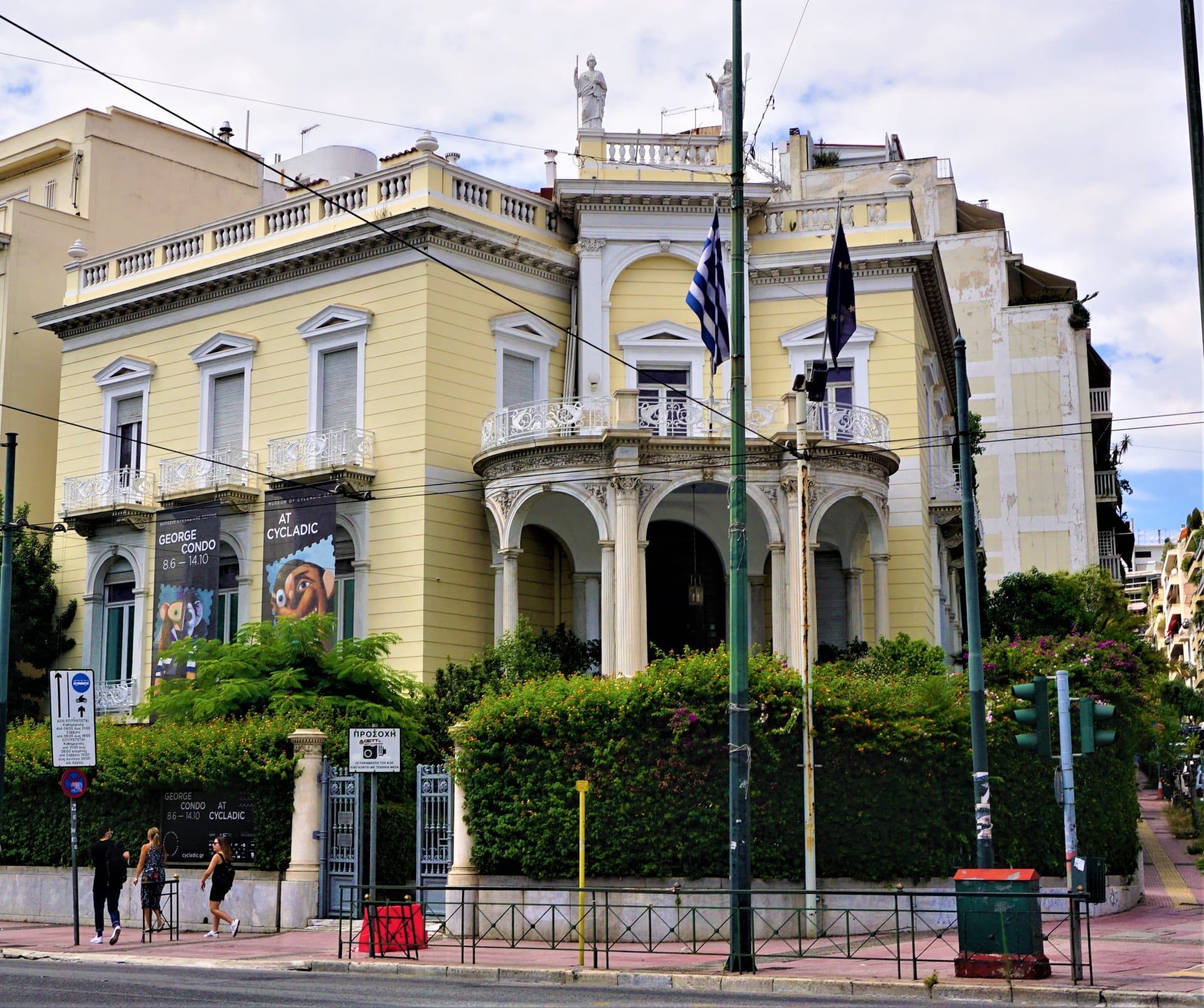 The neoclassical mansion wing of the Museum of Cycladic Art in central Athens, with exhibition banners and Greek flags at the entrance.